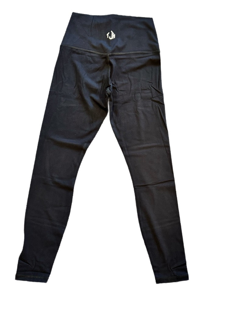 The back of a pair of black, high-performance leggings from #TeamJHall, featuring the TJH logo around the waist.