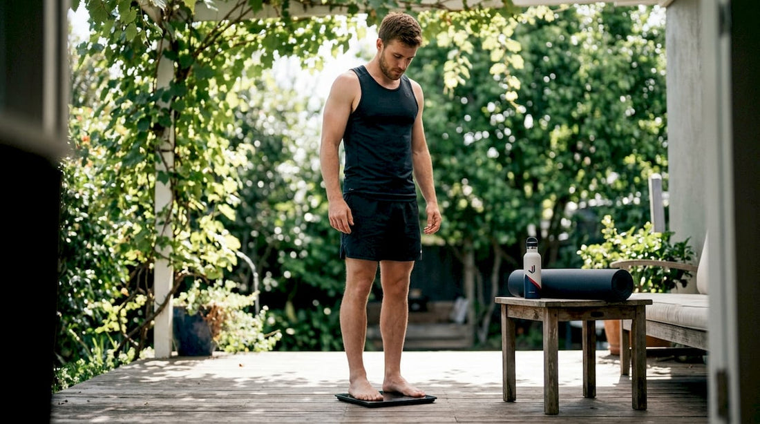 Male athlete weighing himself in home gym